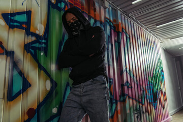 Wall Mural - African american vandal in mask and hoodie crossing arms near graffiti on wall