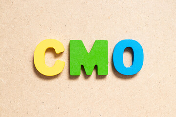 Color alphabet letter in word CMO (Abbreviation of Chief Marketing Officer, Contract Manufacturing Organization) on wood background