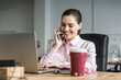 © ADDICTIVE STOCK - Smiling woman having phone call while browsing laptop