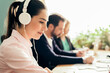 © ADDICTIVE STOCK - Woman in headphones working near colleagues