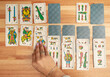 Woman hand playing solitaire card game with Spanish playing cards on a wooden table