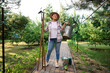 © Taras Grebinets - Full length portrait of a successful cheerful multi-ethnic woman gardener posing with garden tools in the organic farm.