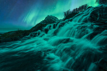 Fast Waterfall Flowing Through Rocks Under Bright Northern Lights
