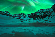 Steep Snowy Mountains Under Starry Sky And Northern Lights