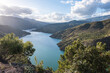 Breath-taking view from the top on green lake surrounded by picturesque mountain alley with trees and bushes in sunny summer day with blue sky and white clouds in background in Spain Andalusia