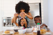 © WavebreakMediaMicro - Multiracial mother with afro hair breaking egg with daughter in bowl while making breakfast on table