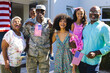 Portrait of happy multiracial army soldier with multigeneration family standing outside house