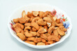 a plate with a pile of peeled roasted salted cashew nuts seeds isolated on white background, cashew tree (Anacardium occidentale) is a tropical evergreen tree that produces the cashew seed and apple