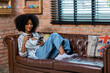 © kanpisut - Young woman consumer holding credit card and smartphone buying online at home. Woman shipping online with credit card in hand. Women using smartphone technology paying credit card shopping online