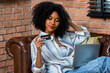 © kanpisut - Young woman consumer holding credit card and laptop buying online at home. Woman shipping online with credit card in hand. Women using laptop technology paying credit card shopping online