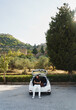 © 22Imagesstudio - Young caucasian man sitting in car trunk during road trip and using phone.