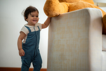 Cute little toddler holding toy while sitting on floor with stuff toy playing with father at home