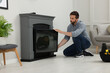 © New Africa - Man installing electric fireplace near wall in room
