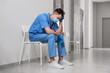 © New Africa - Exhausted doctor sitting on chair in hospital hallway