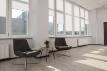Modern Armchairs And Table Near Large Windows With White Roller Blinds Indoors