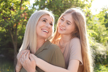 Wall Mural - Happy mother with her daughter spending time together in park on sunny day