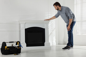 Canvas Print - Man installing electric fireplace near white wall in room