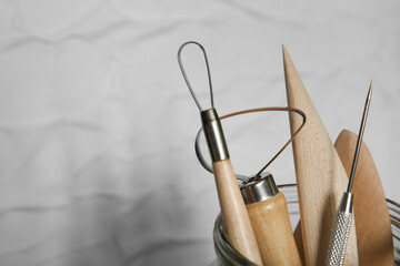 Wall Mural - Set of clay modeling tools in glass jar near white wall, closeup. Space for text