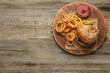 Top view of serving board with tasty burger, French fries and fried onion rings on wooden table, space for text. Fast food