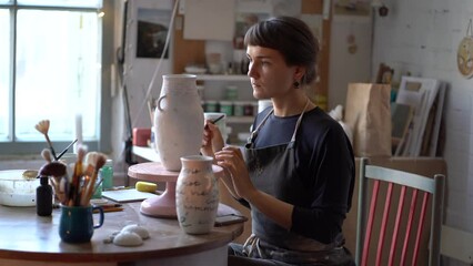 Poster - Creative woman performs individual order in pottery studio for production of clay pots, jag and other various things for home interior decor and gifts. Handmade vases for sale in craft store. 