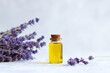 Bottle of lavender essential oil and lavender flowers against grey background. Selective focus
