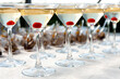 A row of glasses with champagne and cherries inside the glass are on the table.