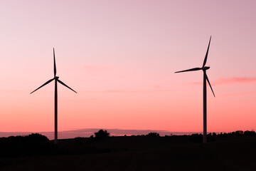 minimal shot of two wind turbines in countryside at sunset