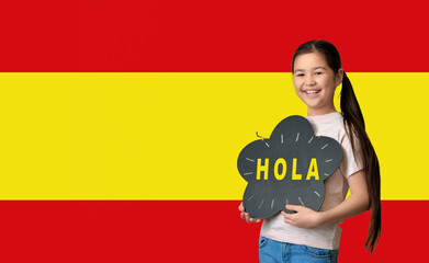 Sticker - Cute little Asian girl holding chalkboard with text HOLA (HELLO) against flag of Spain