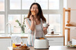 © Pixel-Shot - Beautiful young Asian woman with coffee and tasty toasts in kitchen