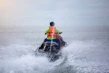 Back View Of Teenager On Jet Ski. Teen Age Boy Skiing On Wave Runner. Young Man On Personal Watercraft In Tropical Sea. Active Summer Vacation For School Child. Sport And Ocean Activity On Beach.