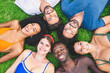 © Lomb - Top view of diverse team of friends relaxing in park lying on grass in circle - multiethnic group of young people having fun in the summer - diversity, union and friendship lifestyle concept