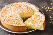 Torta della Nonna is the most delicious Italian custard tart made with sweet shortcrust pastry, custard cream and topped with pine nuts closeup in the plate on the table. Horizontal