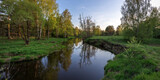 Fototapeta Las - Bright May greens. Picturesque landscape with a small river. Evening pacifying landscape with a river and trees.