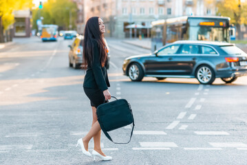 young pretty business woman commuting and walking in city street with laptop bag.side view,copy spac