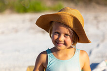 Little Girl Wearing Straw Hat And Smiling At The Camera