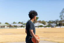 Kid In Black Looking Away Holding Basketball