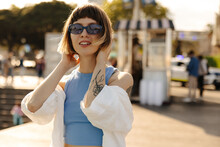 Cute Young Caucasian Girl Brown Hair With Bob Haircut Posing Outdoors In Sunny Weather. Lady Wears Sunglasses, Tank Top And Shirt. Summer Vacation Concept