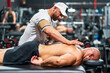 Masseur applying sports back massage to muscular sportsman lying on stretcher
