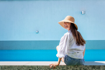 Wall Mural - Woman relaxing by the pool at summer time