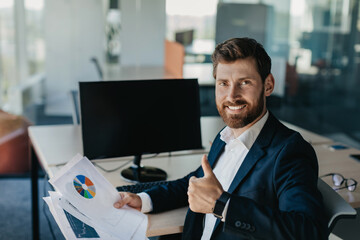 Poster - Portrait of happy businessman showing thumb up and smiling, sitting near blank empty computer monitor at workplace