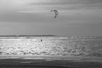 a kitesurfer rides across the north sea in strong winds