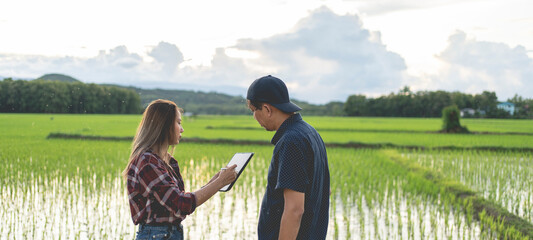 Female and male farmers are consulting using tablets to analyze agricultural product data. Agricultural technology concept.