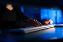 Close-up Hands Of Unrecognizable Hacker Man Working Typing On Keyboard Laptop Computer Sitting At Desk In Dark Room With Blue Neon Lights. Concept Of Cyber Attack, Virus, Malware, Illegally.