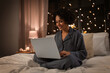 canvas print picture - technology, bedtime and rest concept - happy smiling woman in pajamas with laptop computer sitting in bed at night
