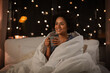 © Syda Productions - people, bedtime and rest concept - happy smiling woman in pajamas with coffee sitting in bed at night