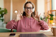 Web-based education concept. Portrait of happy girl wearing headphones studying at online school and geturing ok sign