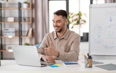 Sticker - distant education, school and remote job concept - happy smiling male teacher with laptop computer and earphones having online class or video call at home office