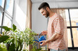 © Syda Productions - people, nature and plants care concept - happy smiling man watering flowers at home