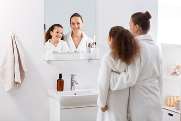 Sticker - beauty, hygiene, morning and people concept - happy smiling mother and daughter looking to mirror at bathroom