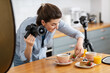 canvas print picture - blogging, profession and people concept - happy smiling female food photographer with camera photographing pancakes, coffee and orange juice in kitchen at home